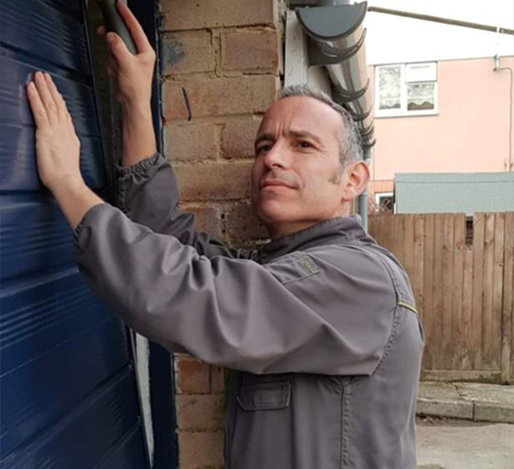 man preparing to fix a blue garage door in a residential area with focus on six crucial details for proper maintenance